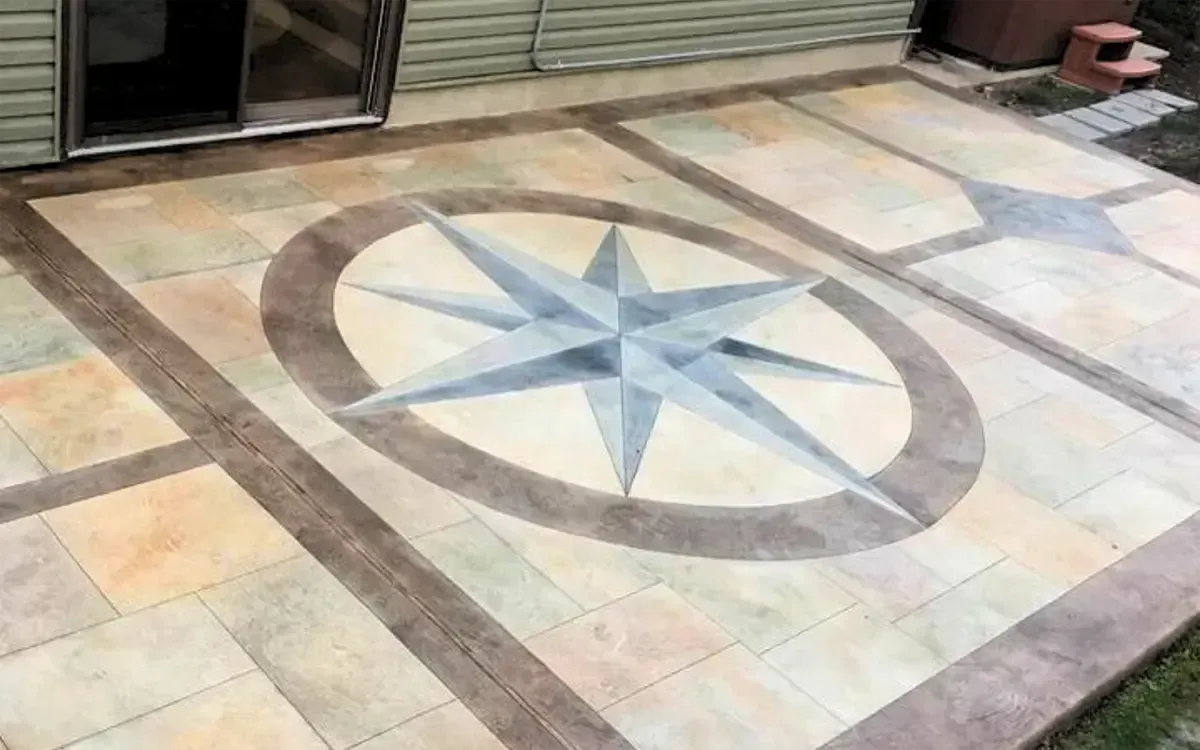 Stone patio with a large compass rose mosaic in the center and brown border tiles