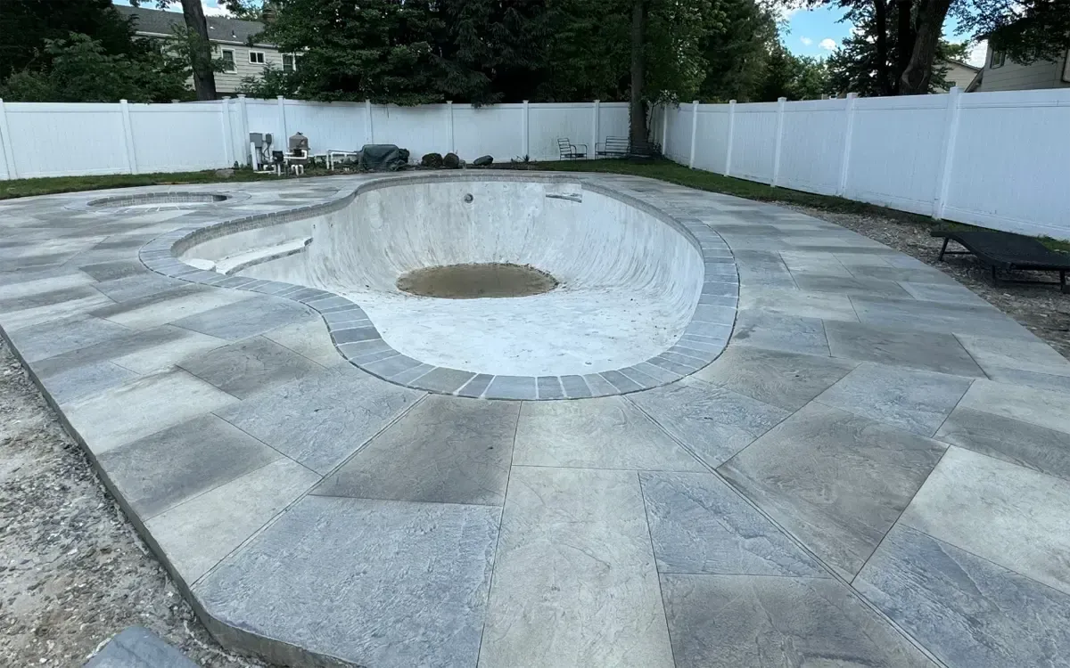 Empty circular concrete courtyard with a raised center, surrounded by white walls and trees.
