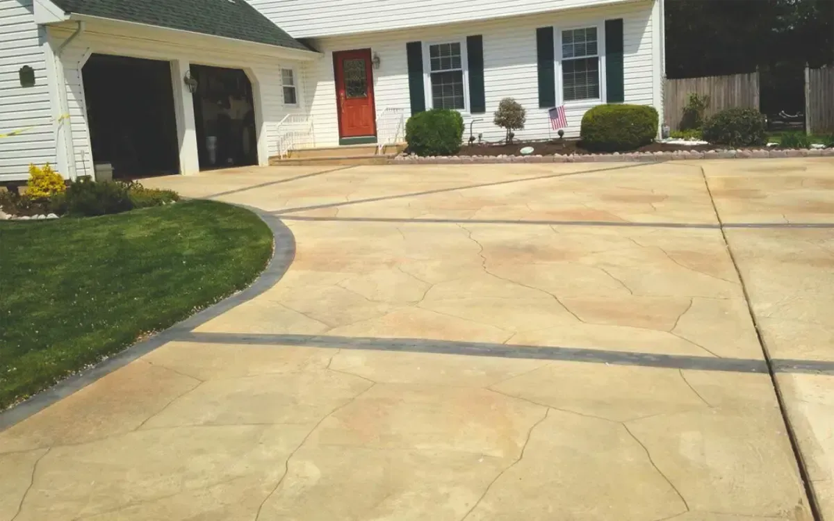 Suburban house with a wide concrete driveway, red front door, and neatly trimmed shrubs.