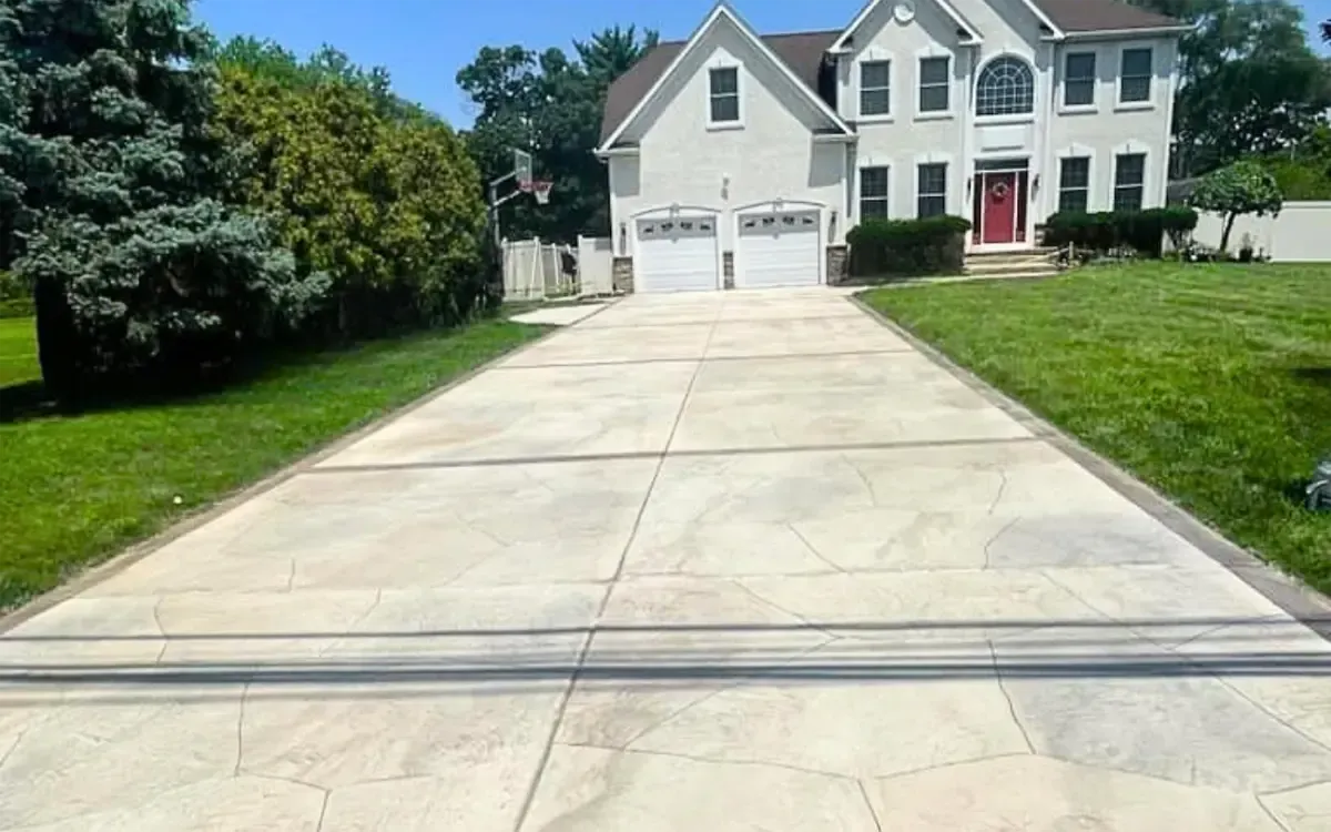Suburban house with a wide concrete driveway and green lawn on a sunny day