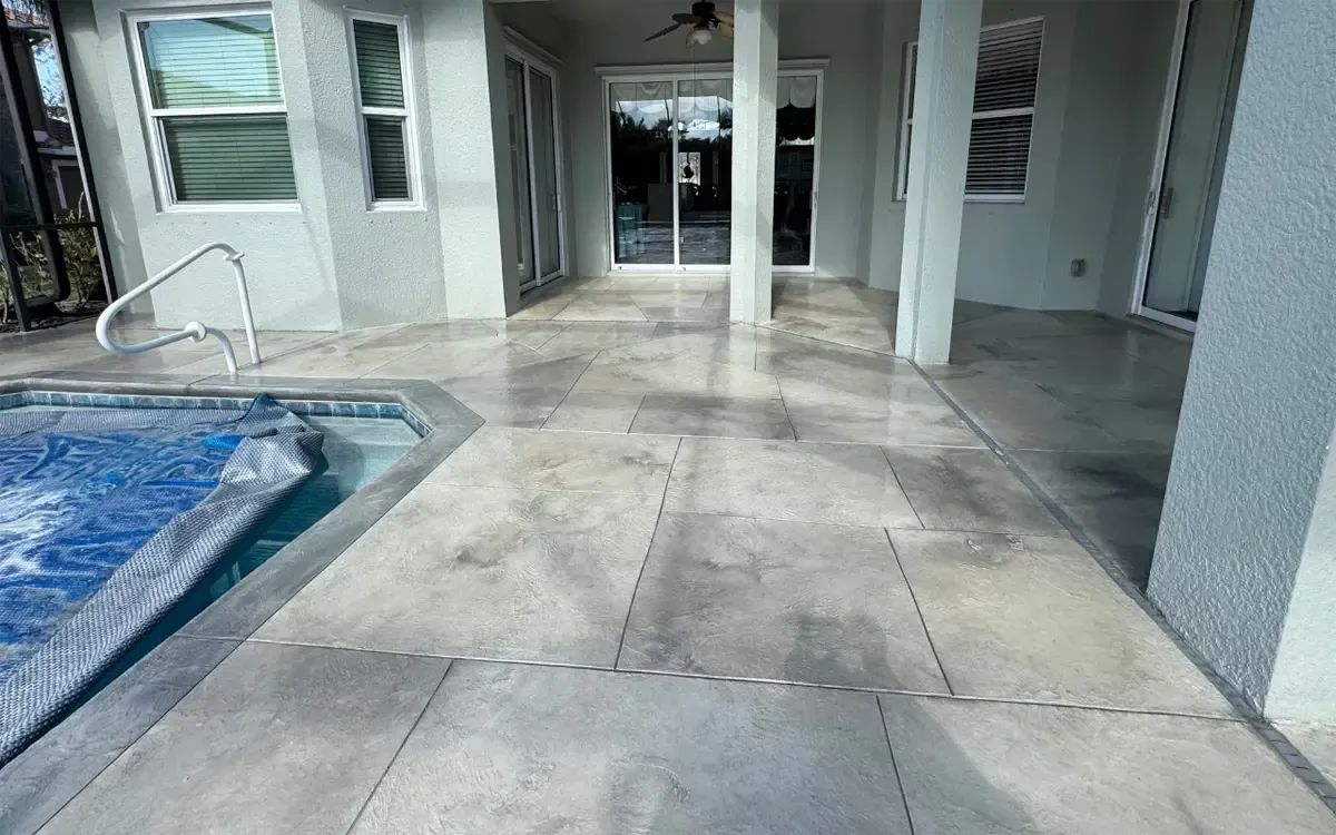 Covered patio beside a small pool with wet concrete and glass doors