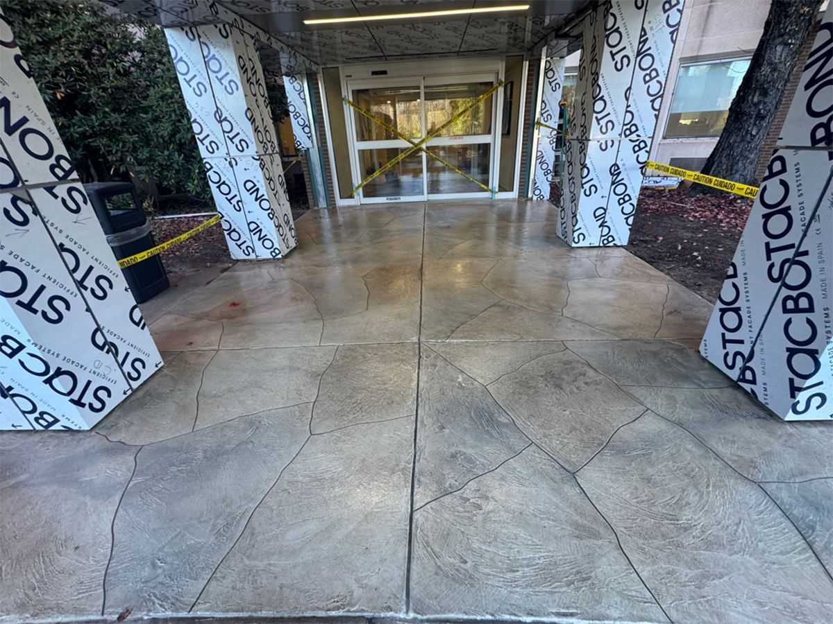 Empty mall corridor with concrete floor, wrapped columns, and glass doors in the distance