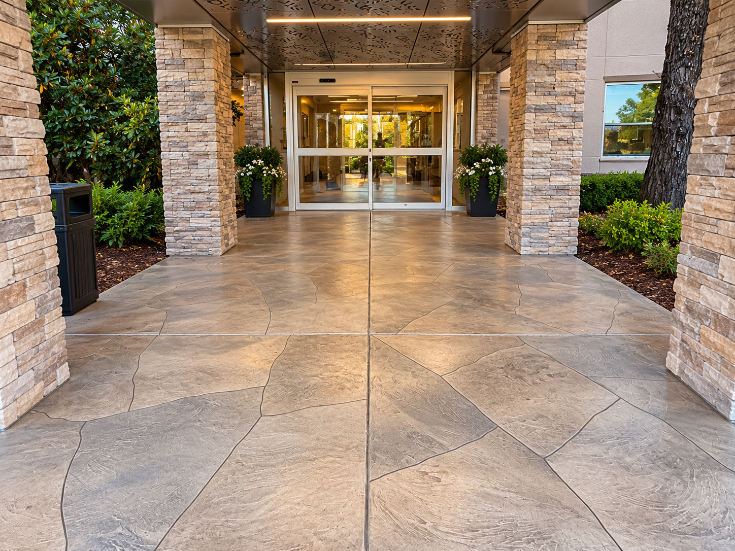 Covered stone walkway leading to glass entrance doors at a building lobby