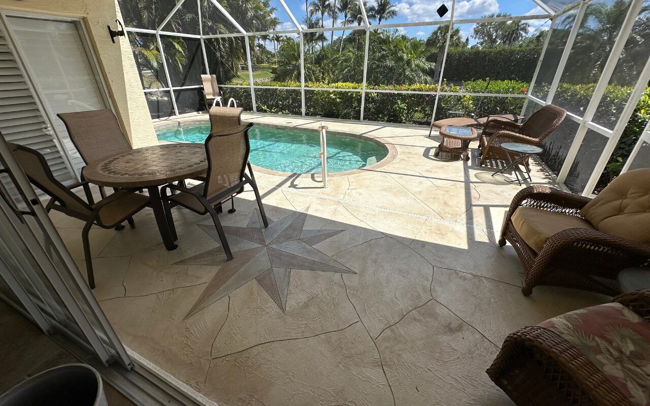 Screened patio with pool, round table and chairs, wicker seating, and tiled floor in sunlight