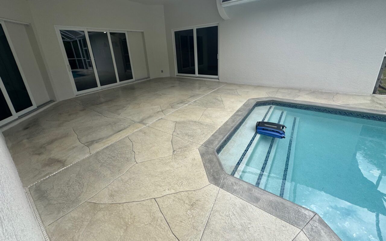 Indoor patio beside a swimming pool with beige stone flooring and sliding glass doors