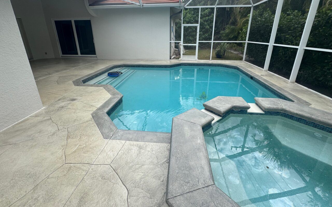 Indoor screened-in pool and hot tub with light blue water and stone deck
