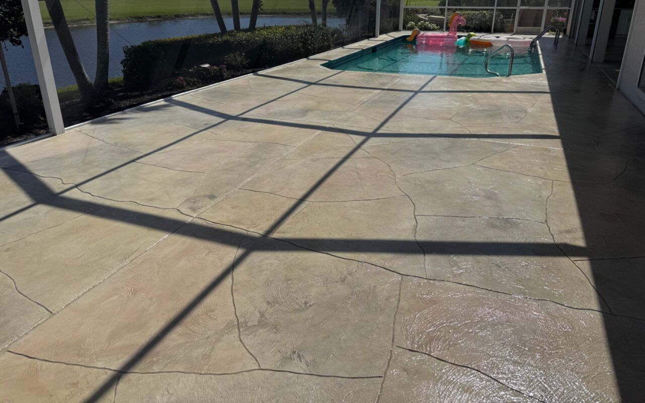 Concrete pool deck beside a swimming pool, with long shadows cast across the pavement.