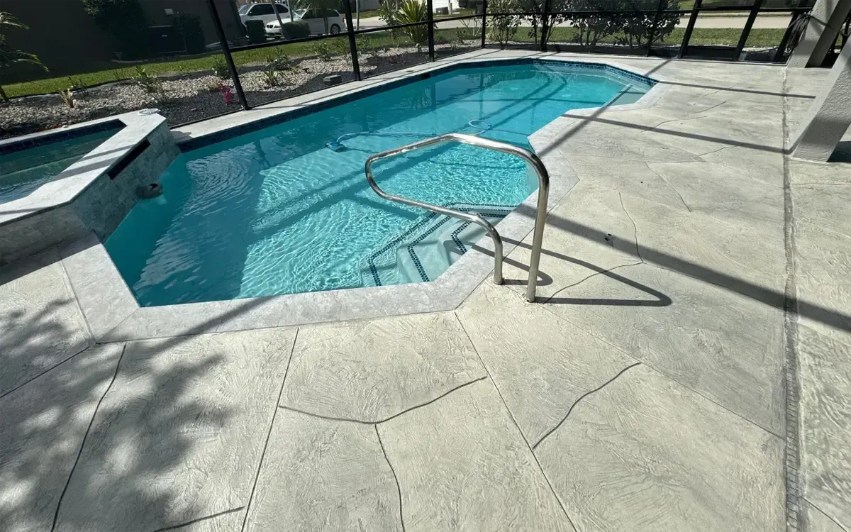 Outdoor swimming pool with a curved handrail and concrete deck in bright sunlight