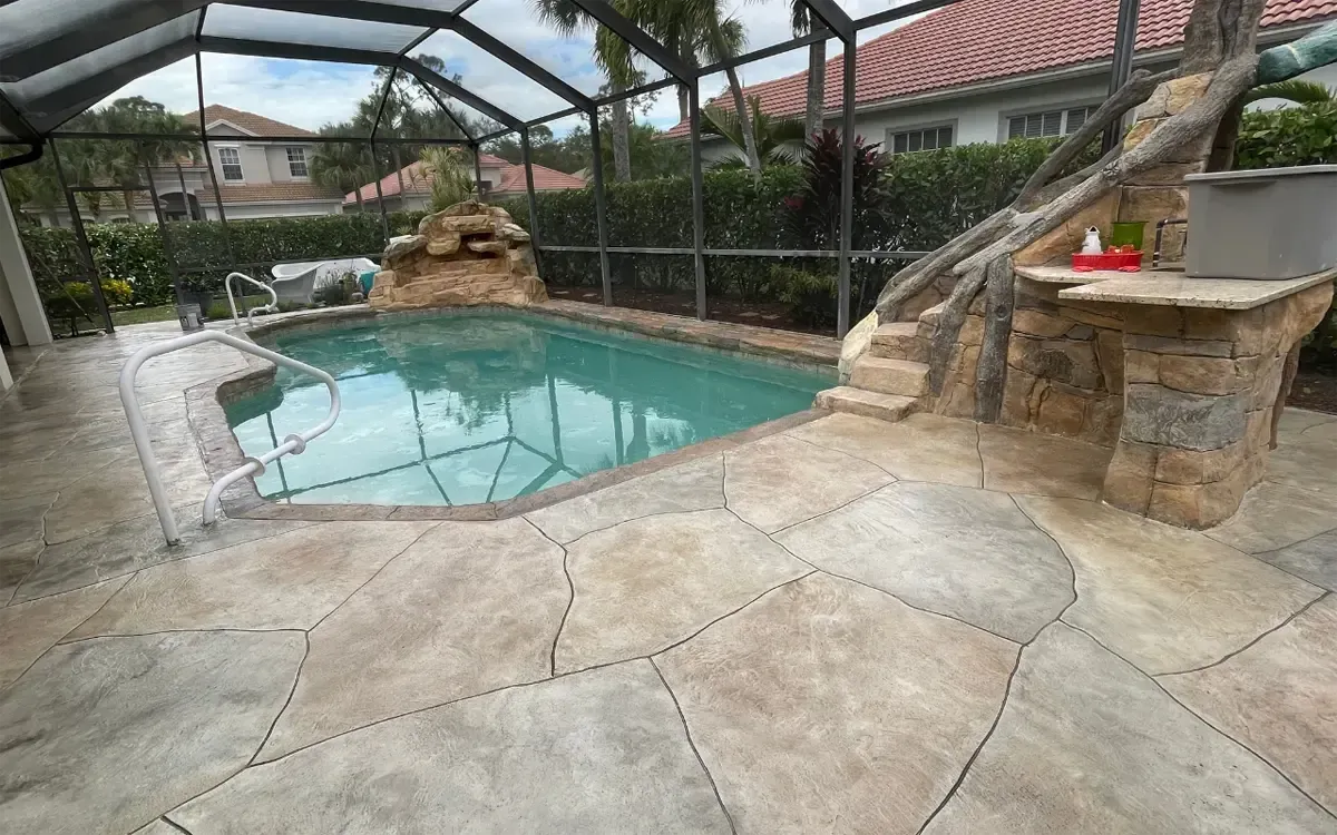 Backyard pool with stone patio, screened enclosure, and a small rock waterfall feature