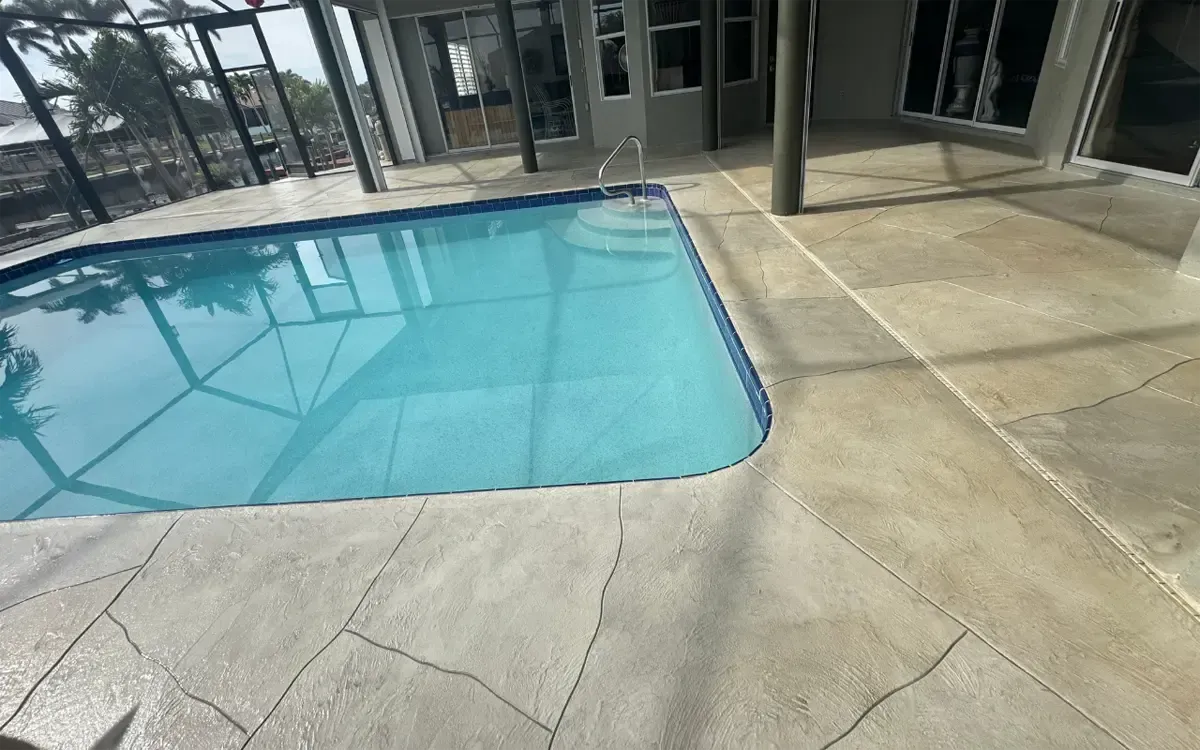 Covered outdoor pool beside a concrete patio and glass-walled building
