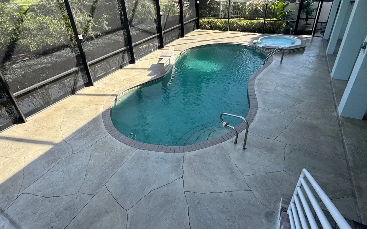 Backyard pool with turquoise water, concrete deck, and screened lanai enclosure