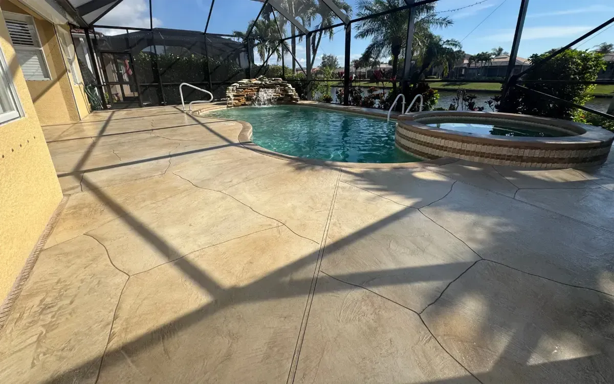 Backyard pool patio with tan tile, palm shadows, and a round hot tub beside the water