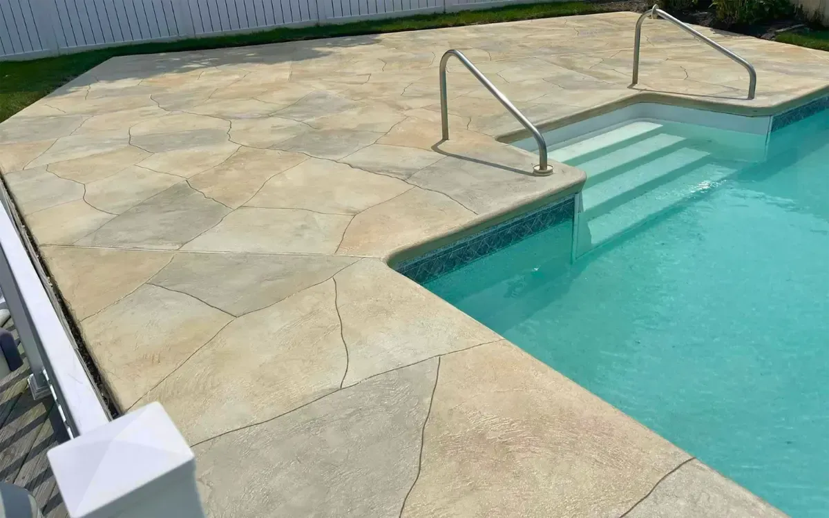 Stone pool deck with metal handrails and turquoise swimming pool steps