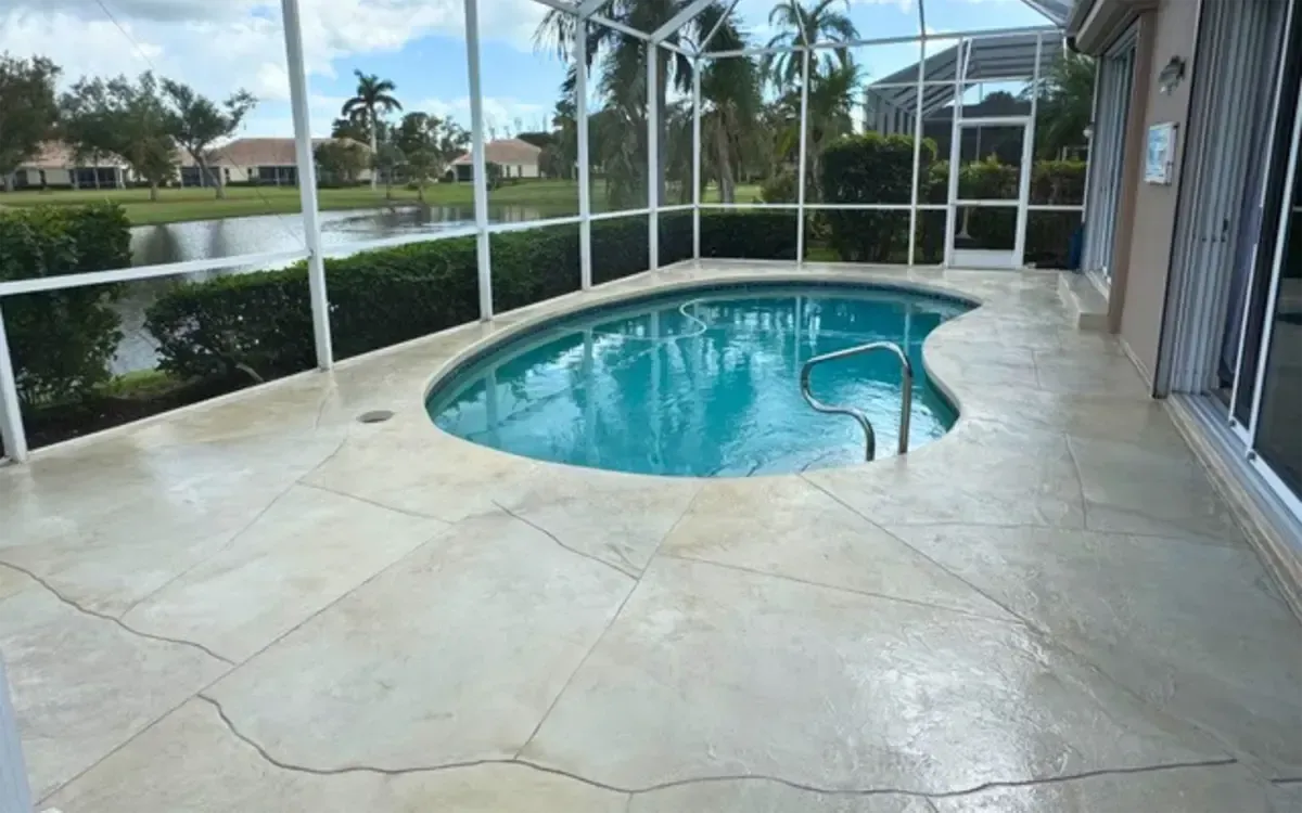 Screened patio with a small turquoise pool and wet concrete deck overlooking a lake