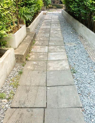 A brick walkway leading to a lush green garden.