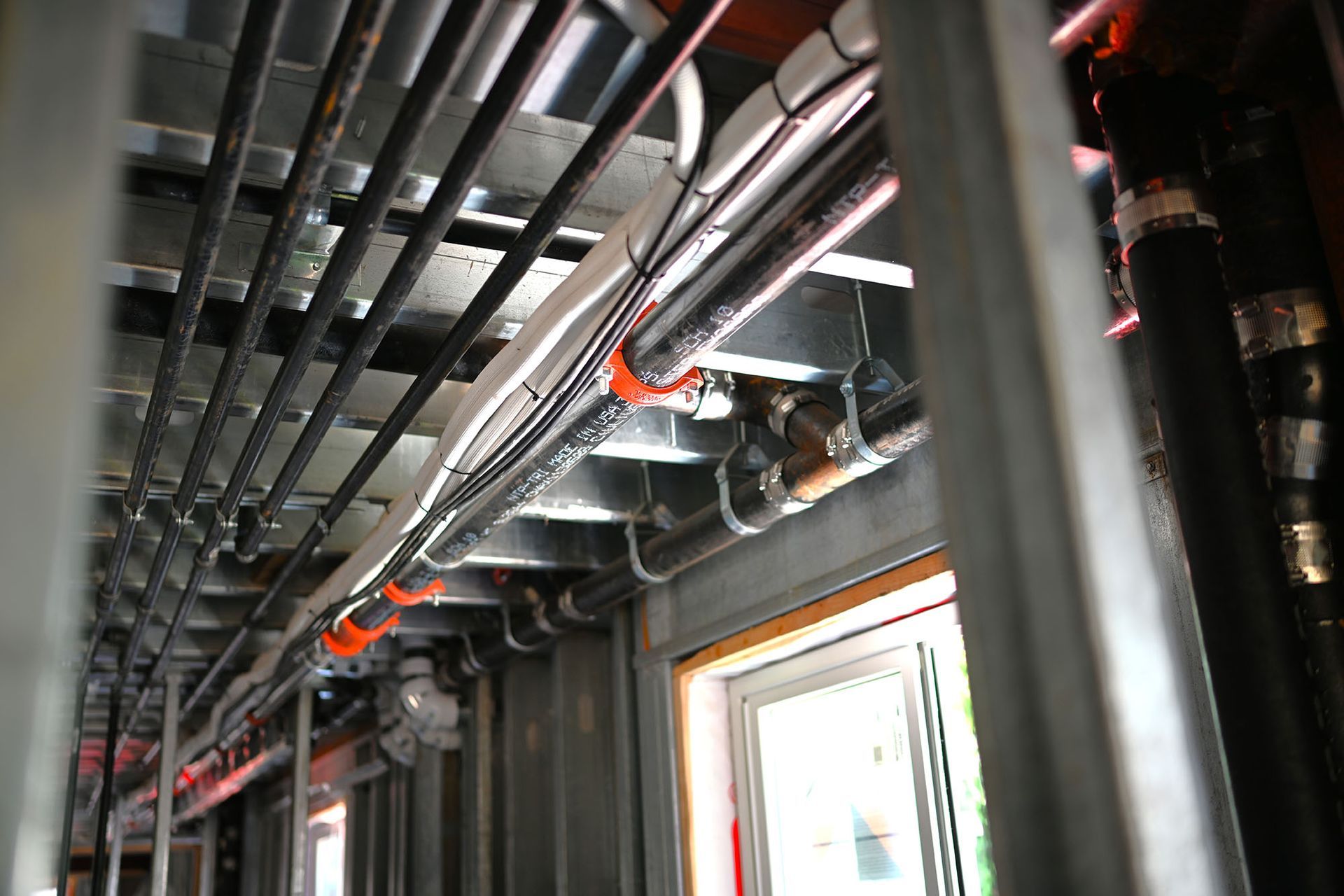 A bunch of pipes are hanging from the ceiling of a building.