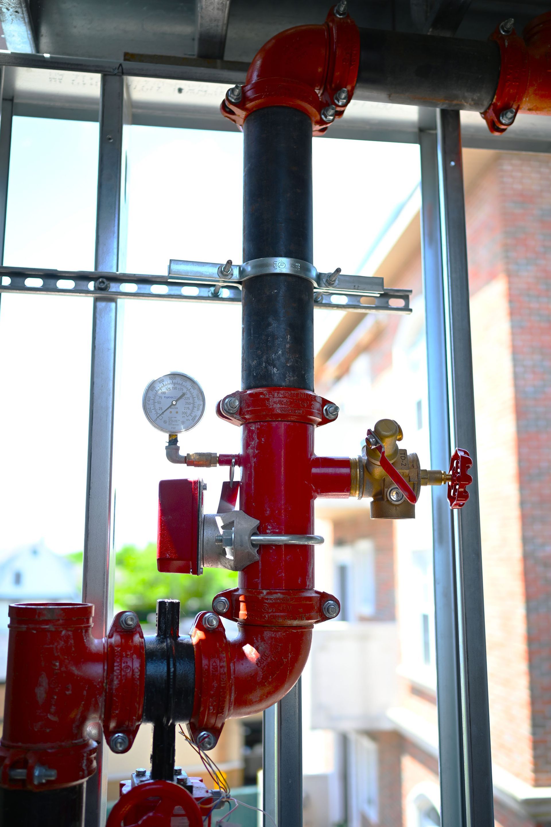 A close up of a red pipe with a gauge attached to it.