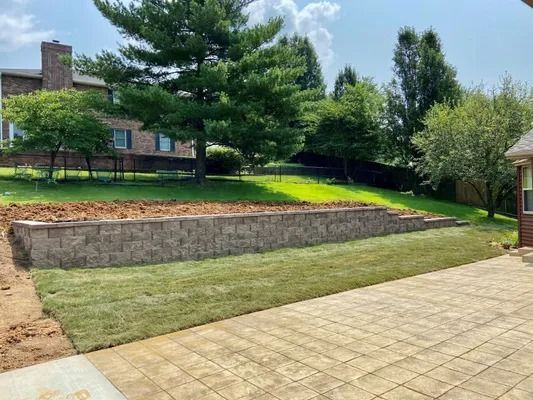 Retaining wall with new grass and patio in a backyard setting.