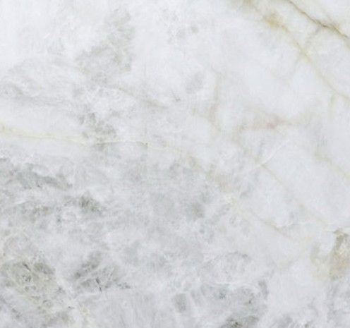 A close-up of white marble stone with faint grey and gold veining throughout.