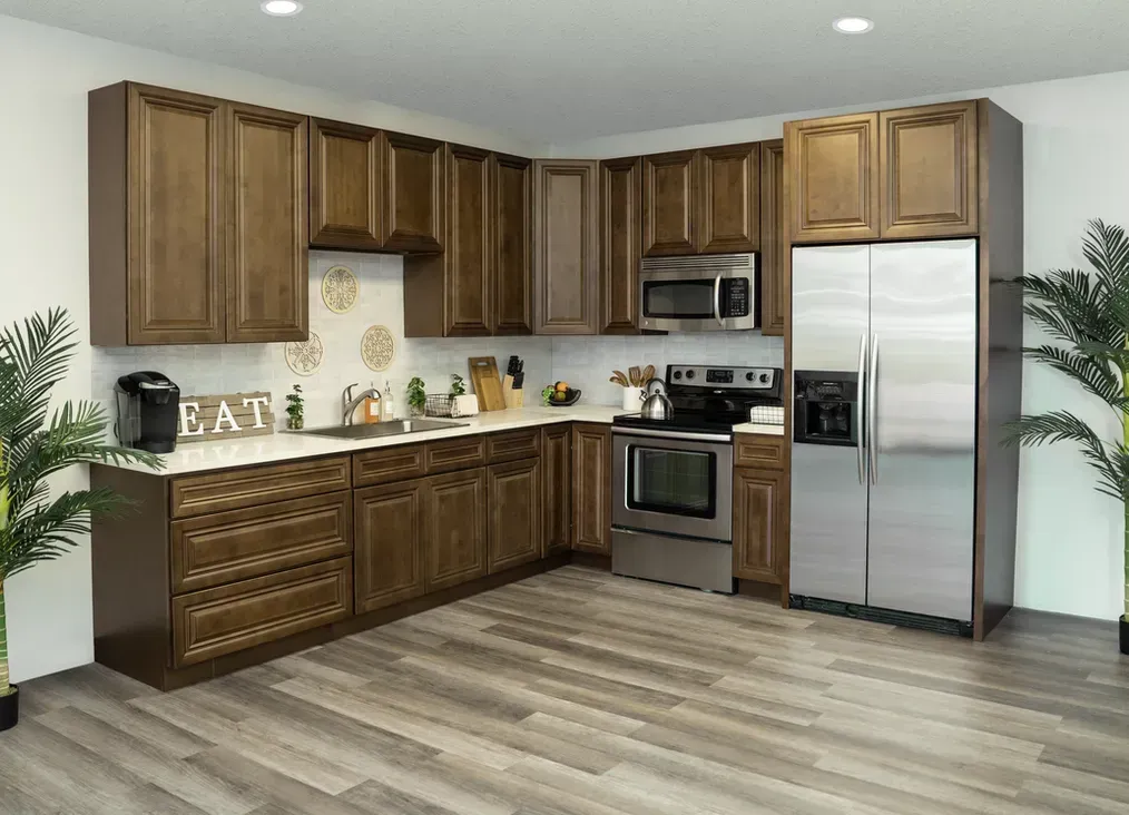 Brown kitchen cabinets with stainless steel appliances, light countertops and wood flooring.