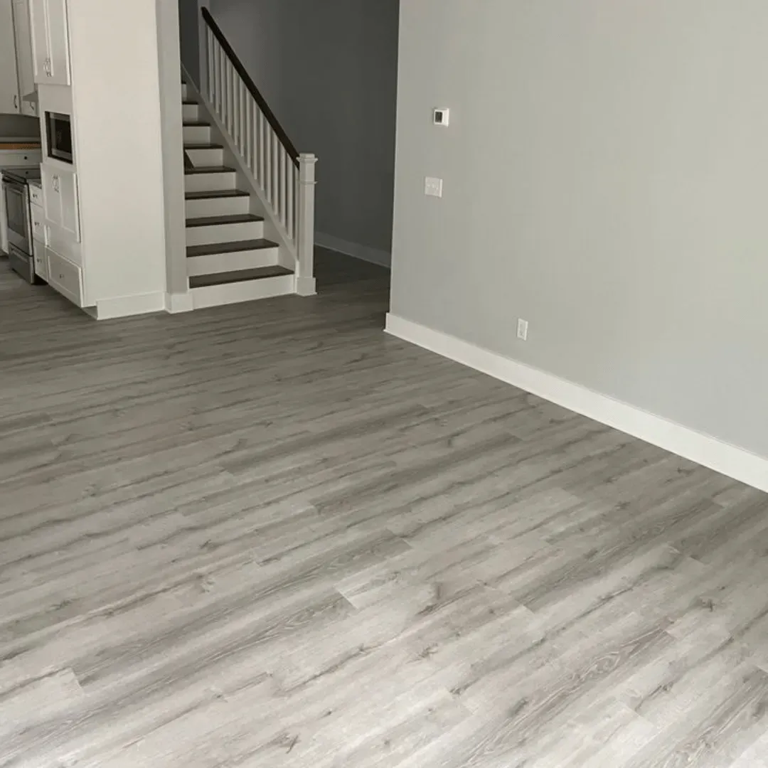 Room interior with gray wood-look flooring, light gray walls, and a staircase.