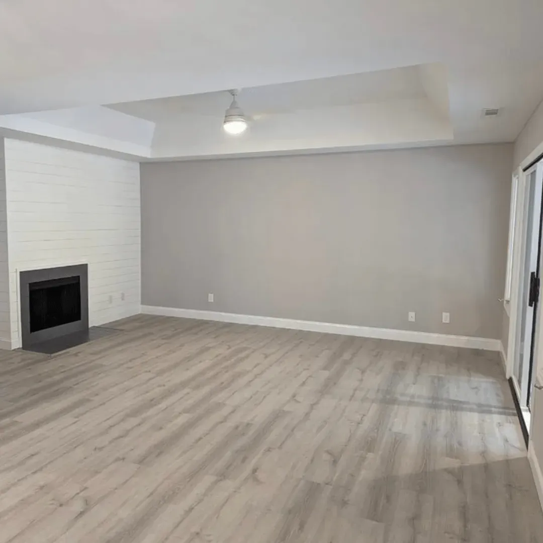 Empty living room with fireplace, gray walls, white ceiling, and light wood flooring.