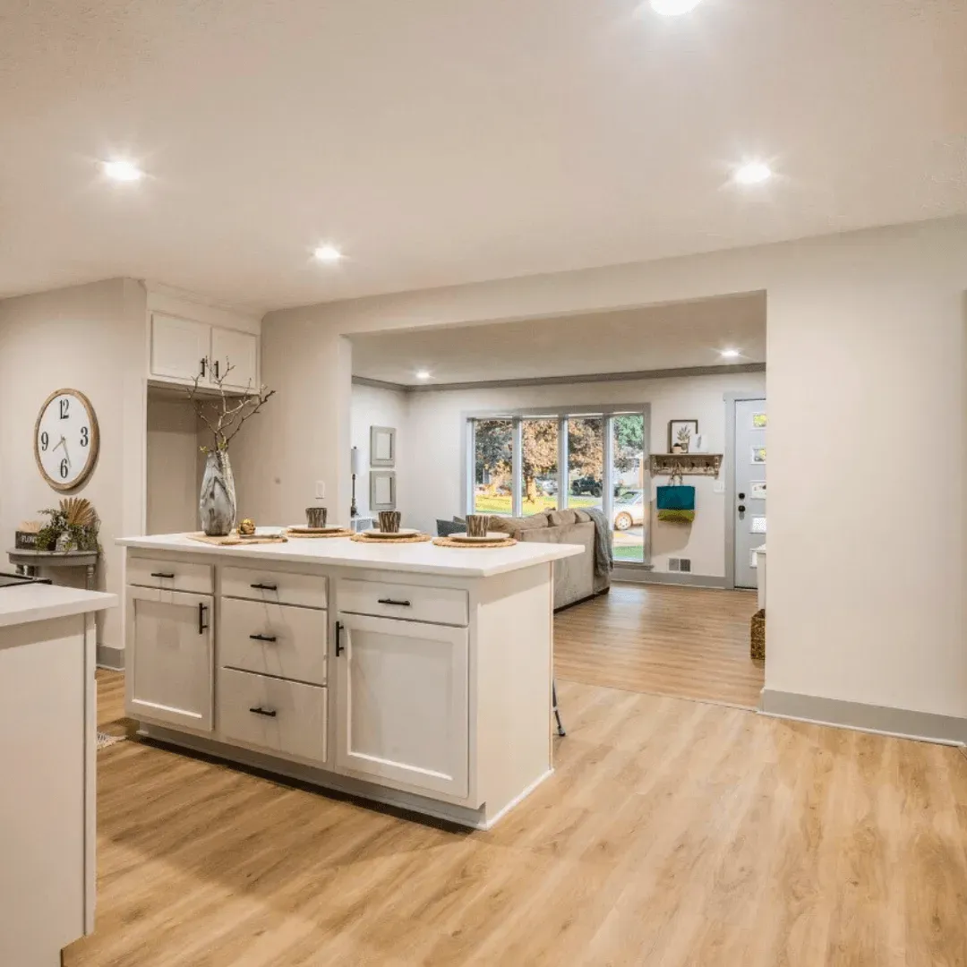 Open kitchen with island, cabinets, and a view into the living area with hardwood floors.