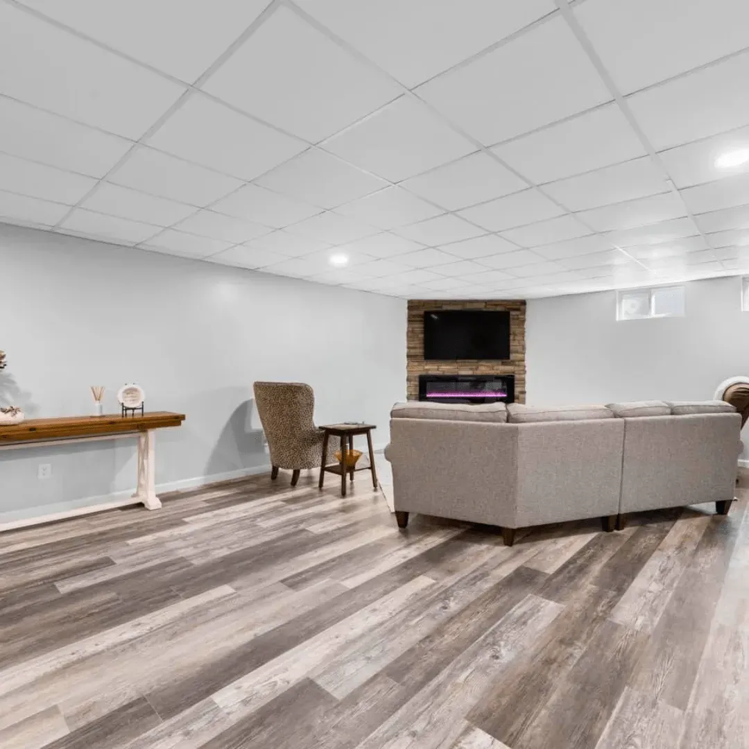 Living room with wood flooring, light grey sectional sofa, and a fireplace with a TV.