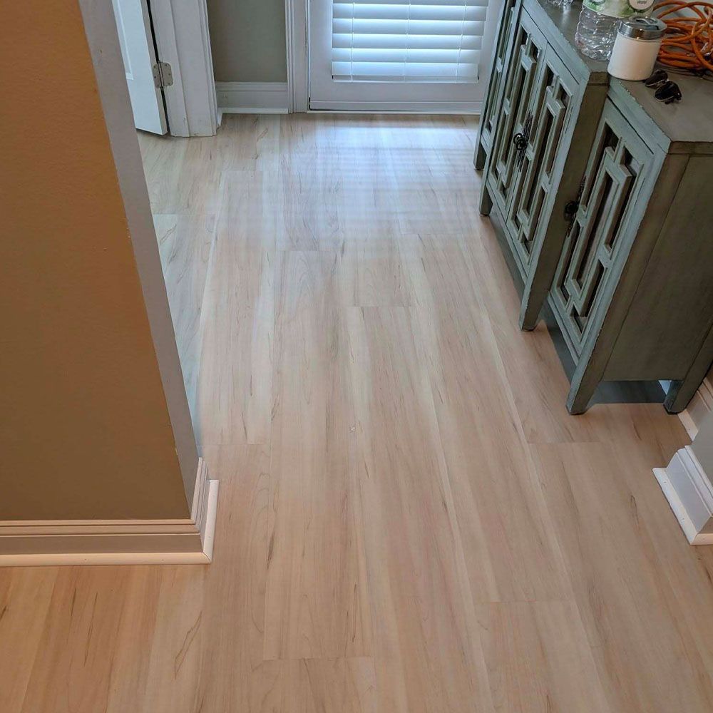 Light wood-look flooring extends from the doorway. A green cabinet sits on the right. Beige walls are visible.