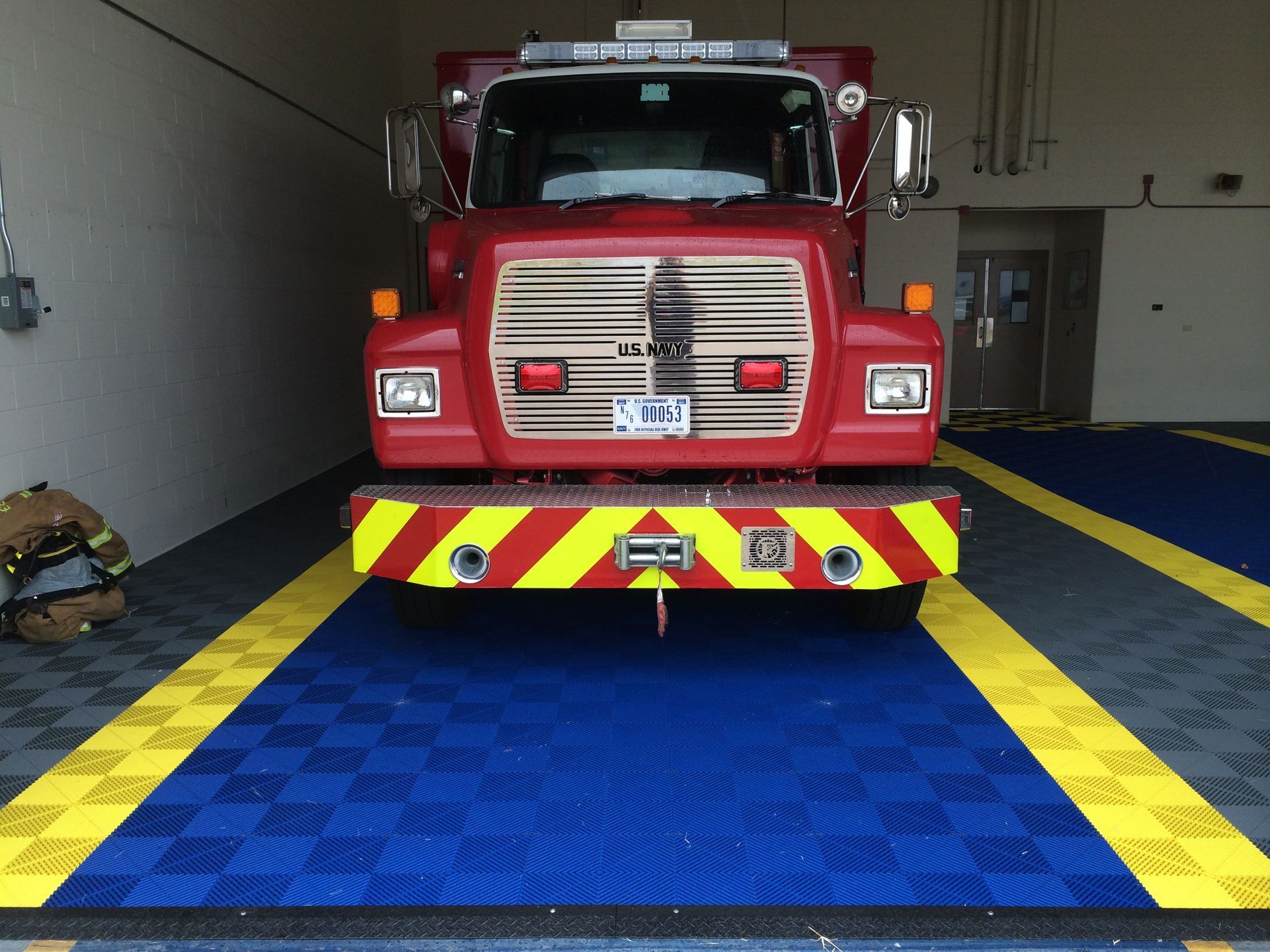 Fire truck parked inside a garage, with blue and yellow checkered floor.