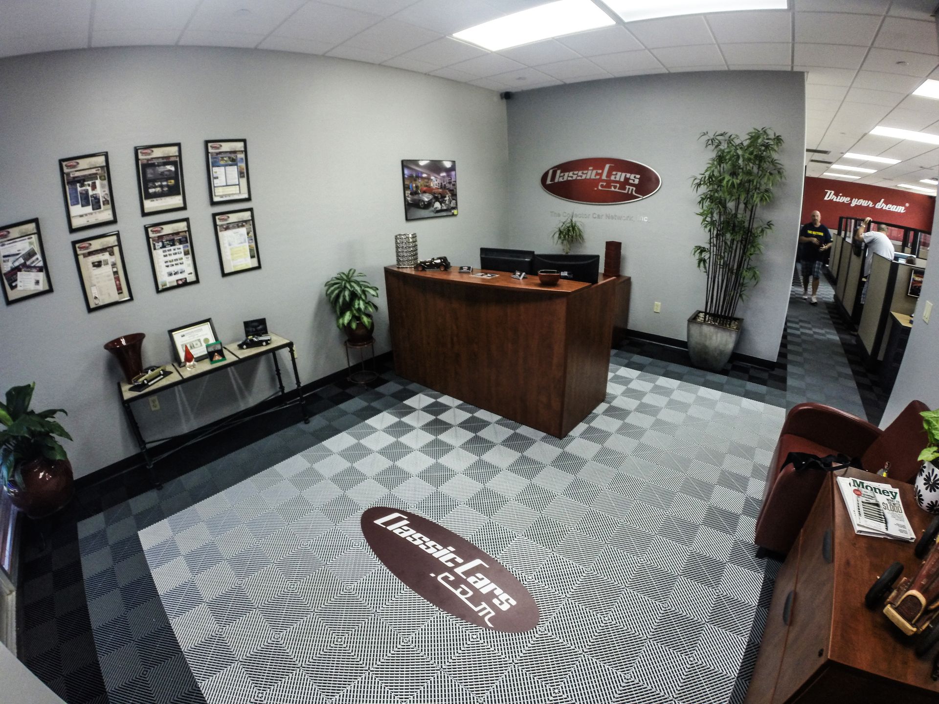 Reception area with brown desk, patterned floor, and awards on the wall.
