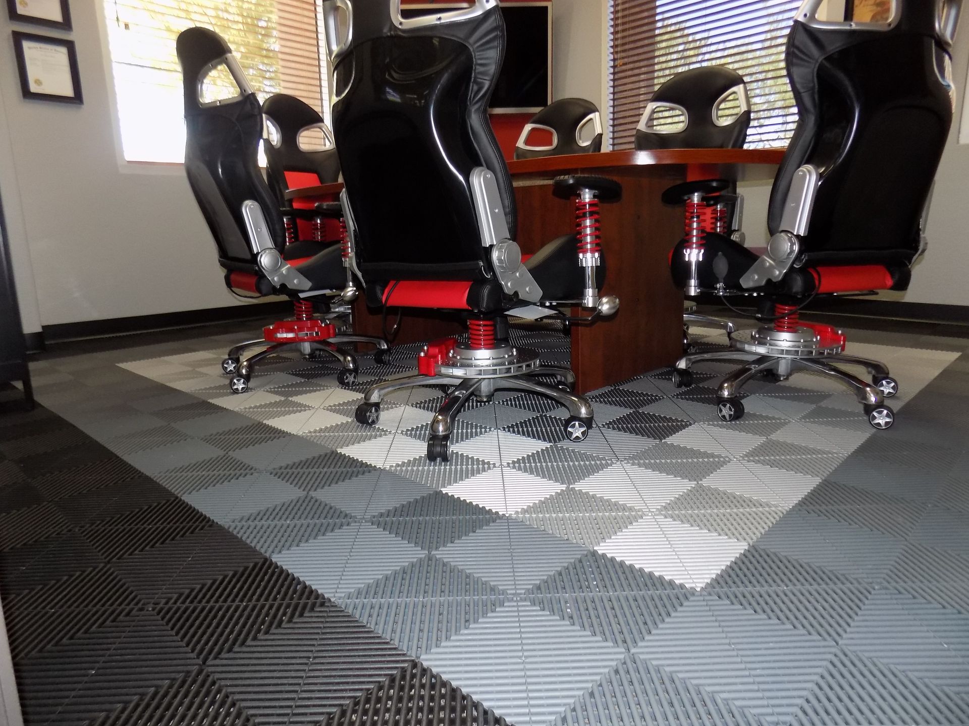 Office with racing-style chairs and checkered flooring; dark and red accents.