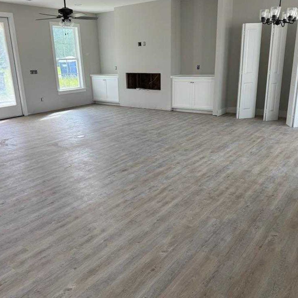 Empty living room with light wood-look flooring, built-in cabinets, fireplace, and unfinished walls.
