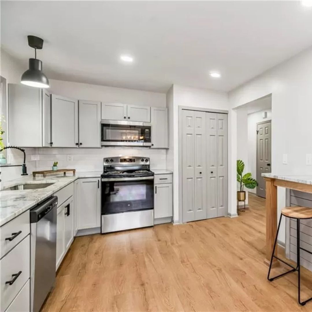 Kitchen with gray cabinets, stainless steel appliances, and wooden flooring.