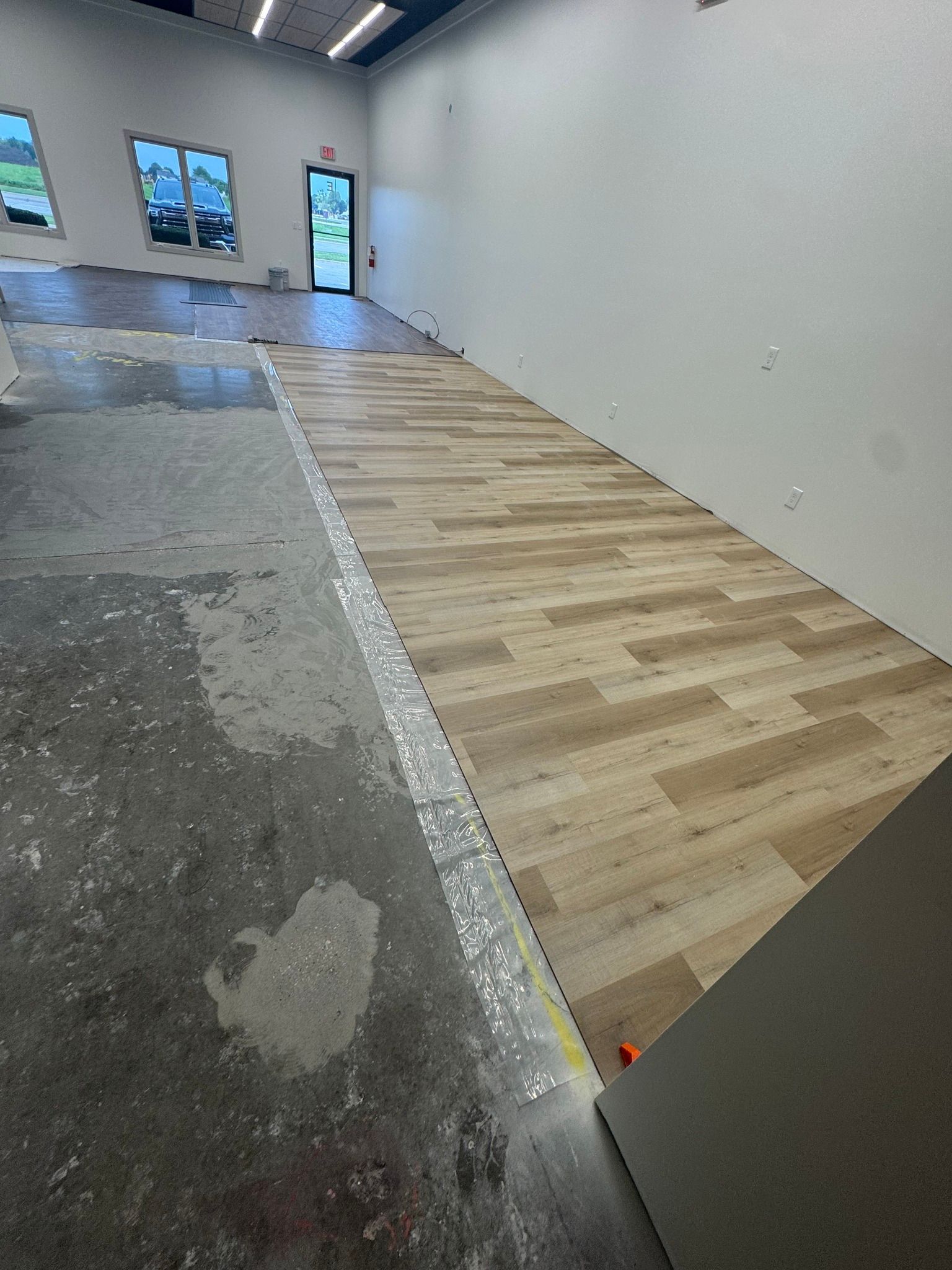 interior view: concrete floor being tiled with wood-looking planks