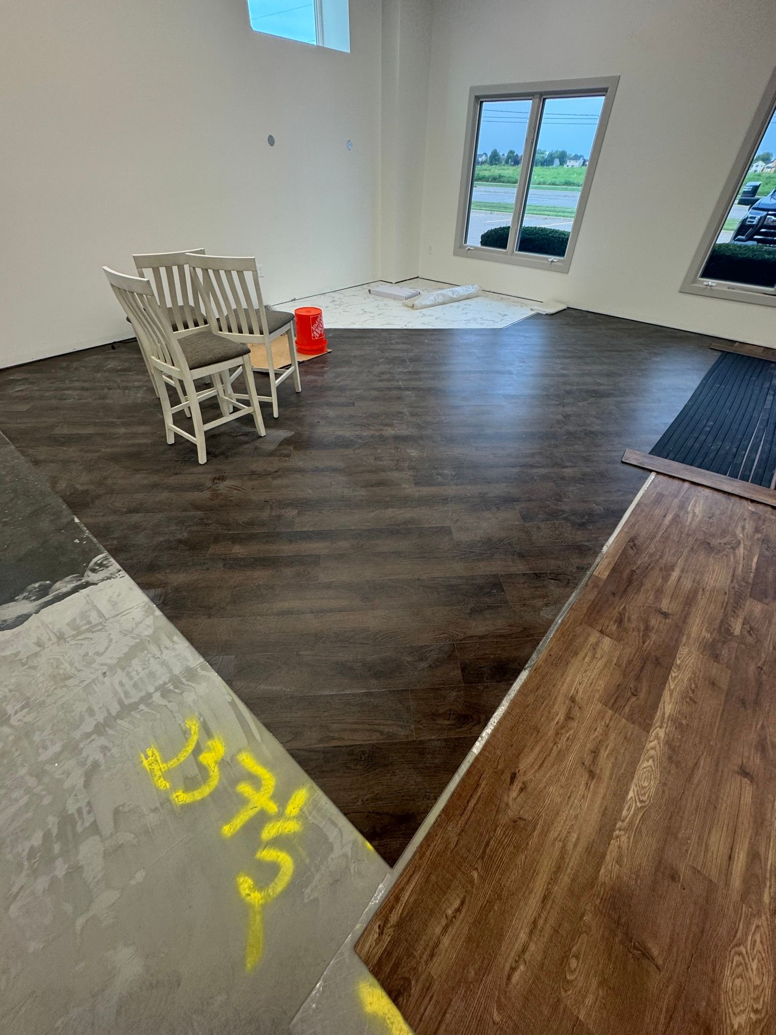 interior view of a room with installed dark brown flooring and white walls, two white chairs