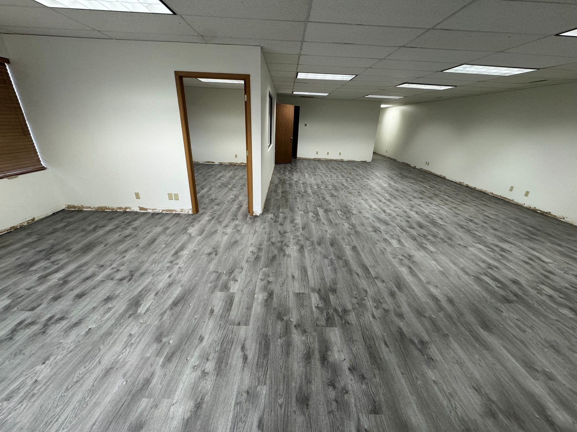 empty office space with gray wood-looking flooring, white walls, and a recessed ceiling