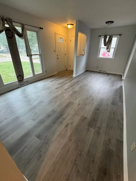 living room with gray wood-looking flooring, windows, a door, and gray and white walls