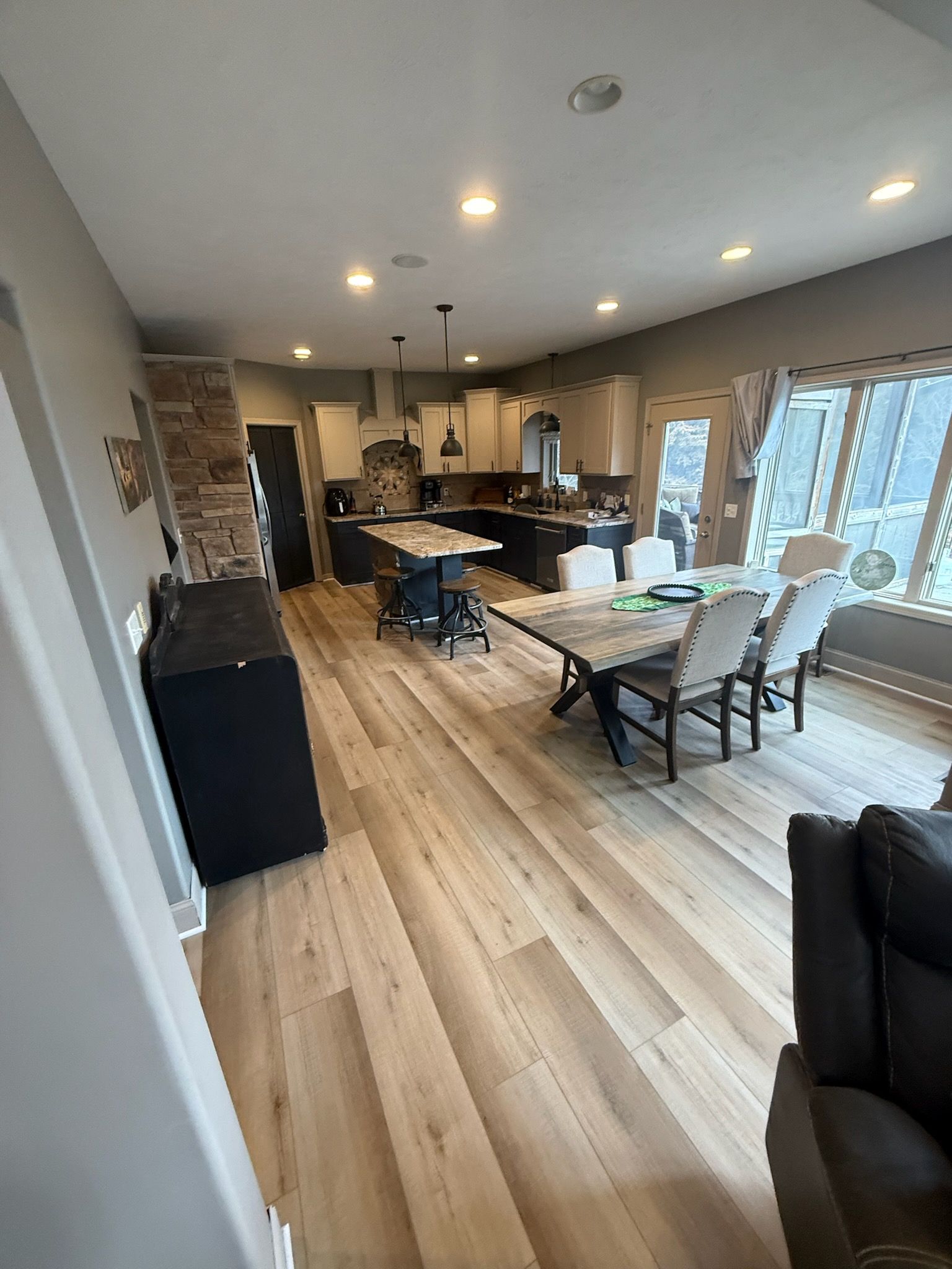 Open-plan kitchen and dining area with light wood floors, island, dining table, and large windows