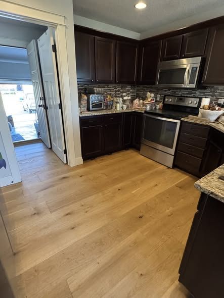 kitchen with dark cabinets, stainless steel appliances, and light wood flooring