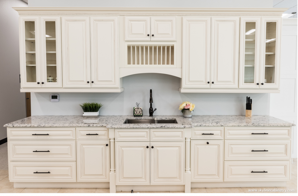 Cream-colored kitchen cabinets with granite countertop and black faucet.