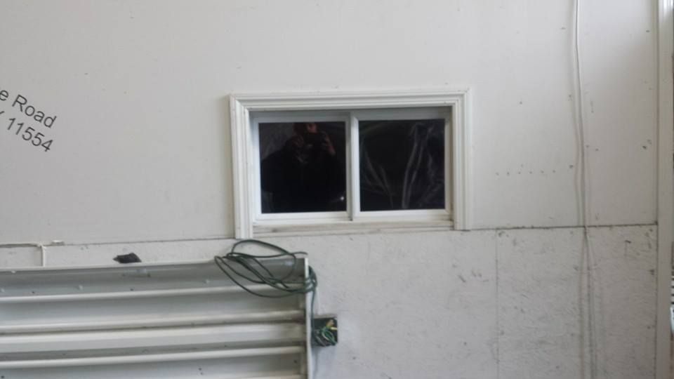 A small white-framed sliding window installed on a white interior wall above a metal radiator.