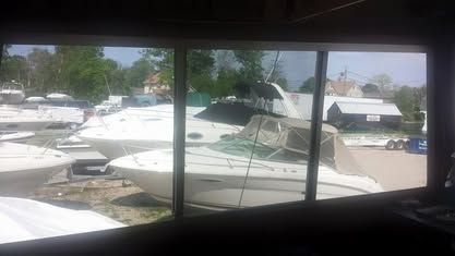 View through a window of a boat storage yard with several white boats parked on trailers.