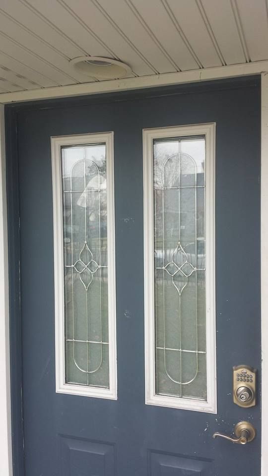 A dark blue exterior door with two long, vertical windows featuring decorative silver trim and a silver handle and lock.