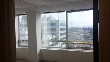 A view from inside an office building looking through large windows at another building and an overcast city skyline.