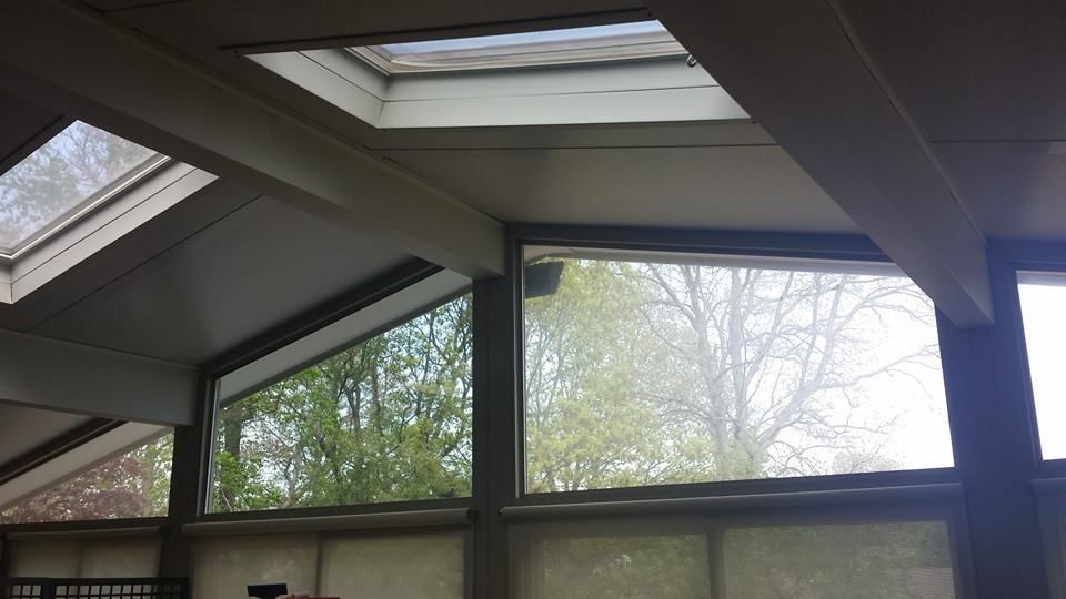 Interior view of a slanted ceiling with two skylights and large windows looking out onto trees.