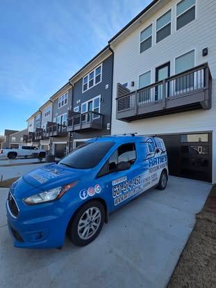 A blue van parked in front of modern townhomes on a clear day.