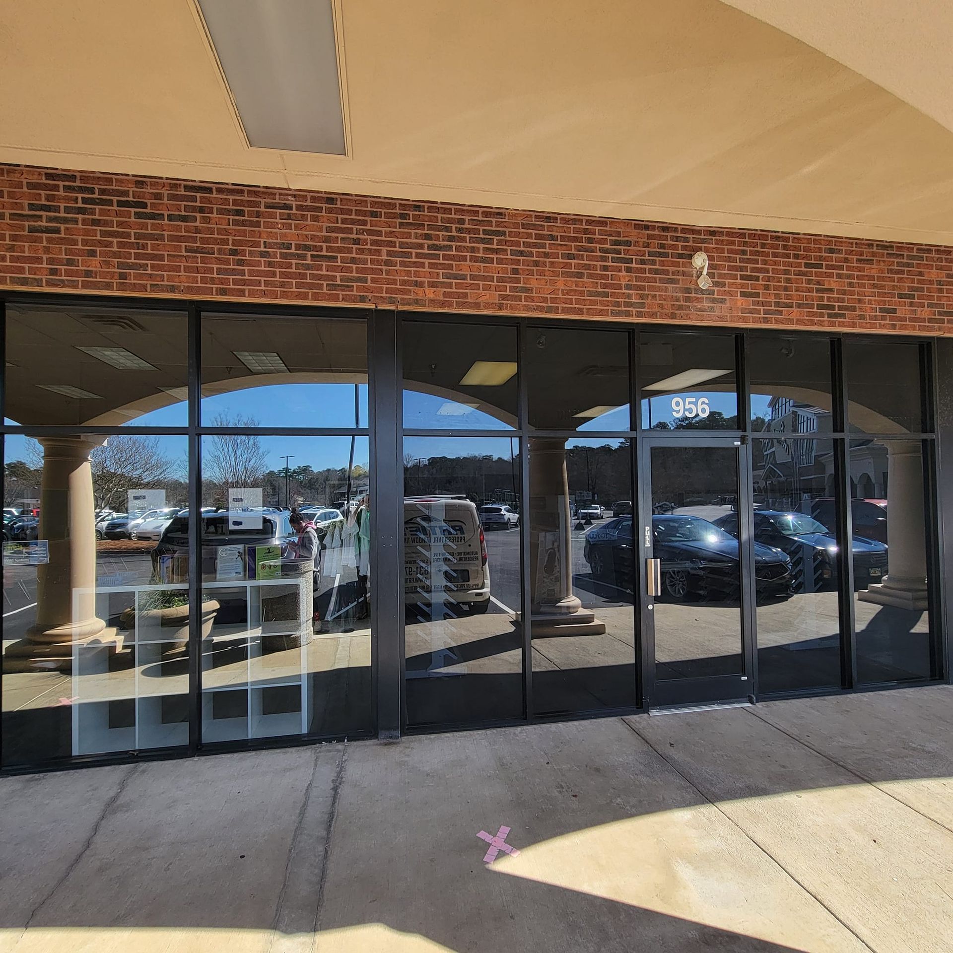 A storefront with a brick facade, glass windows, and a set of double glass doors marked with the number 966.