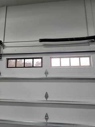 A white garage door interior showing two rectangular windows, one with a dark frame and the other with a white frame.