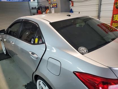 A silver sedan parked inside a garage, showcasing the rear passenger side, roof, and trunk area.
